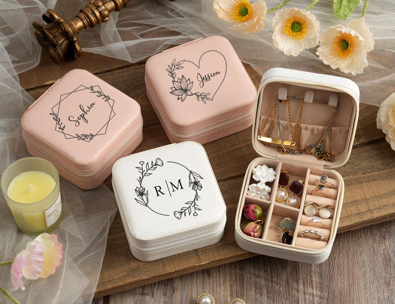 May include: Three pink and white jewelry boxes with floral designs and personalized names. The boxes are open to reveal compartments for rings, earrings, and necklaces.