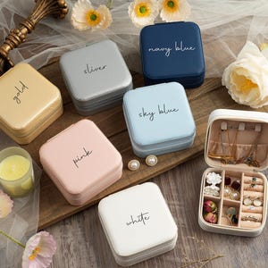 May include: Assortment of ten small jewelry boxes with different colors and labels. The boxes are made of cardboard and have a velvet interior. The labels include: gold, sliver, navy blue, sky blue, pink, white.