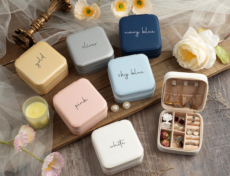 May include: Assortment of ten small jewelry boxes with different colors and labels. The boxes are made of cardboard and have a velvet interior. The labels include: gold, sliver, navy blue, sky blue, pink, white.