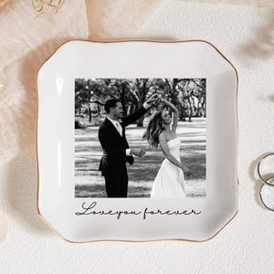 Może przedstawiać: Biały ceramiczny talerz na pierścionki ze złotą obw&oacute;dką, z czarno-białym zdjęciem tańczącej pary. Na talerzu napis "Love you forever". Obok dwa srebrne pierścionki.