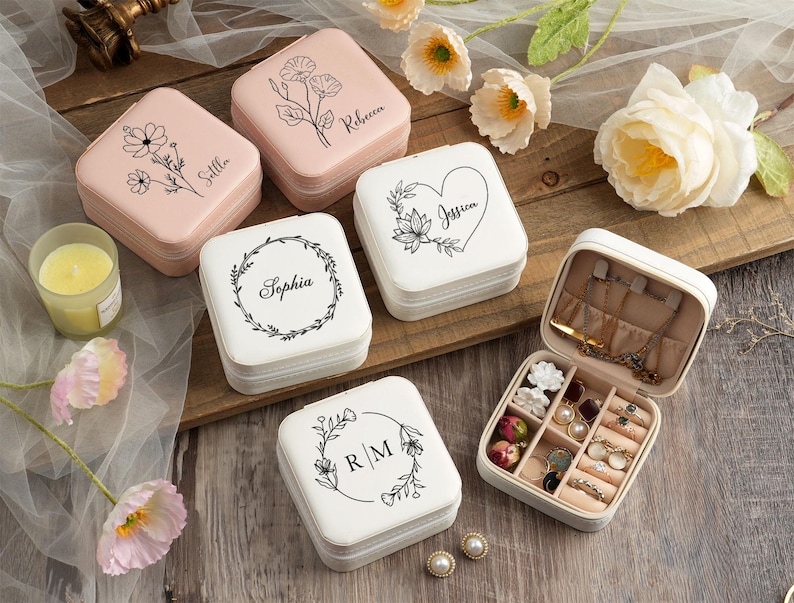 May include: Set of six white and pink jewelry boxes with floral designs and personalized names. The boxes are arranged on a white surface with flowers.