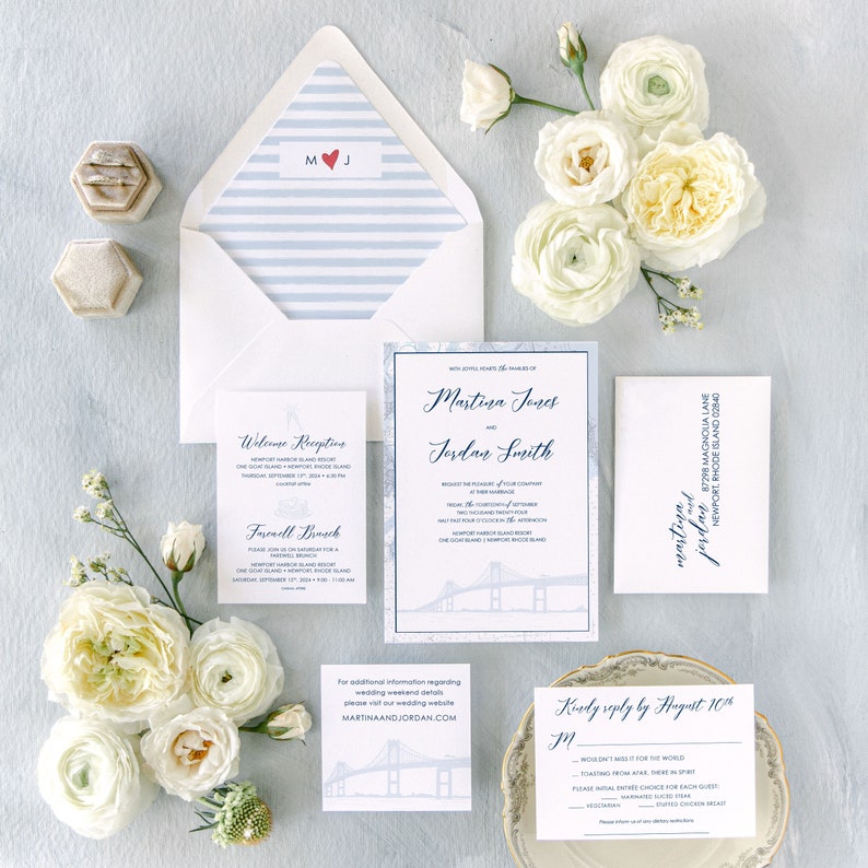 Op de afbeelding: Huwelijksuitnodigingsset met een blauw-wit gestreepte envelop, een witte envelop met de namen "Martina Jones" en "Jordan Smith" erop gedrukt, en een witte kaart met de tekst "Kindly reply by August 10th" erop gedrukt. De uitnodiging toont een kaart van Newport, Rhode Island, met een brug op de achtergrond.