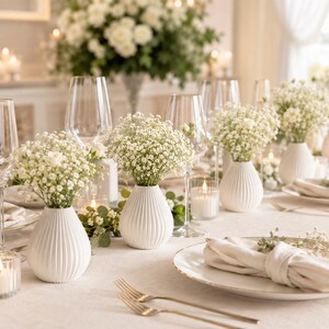 Puede incluir: Elegante mesa decorada con flores blancas en jarrones blancos texturizados. Copas de vino transparentes, velas y platos con borde dorado completan el sofisticado arreglo. Perfecto para una ocasi&oacute;n especial.