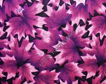 May include: Purple and pink maple leaf fabric with a black background. The fabric is printed with a repeating pattern of maple leaves. The fabric is measured with a ruler in inches.