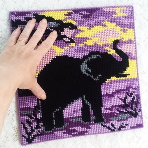May include: Purple and black cross-stitch artwork depicting an elephant silhouette against a sunset background.