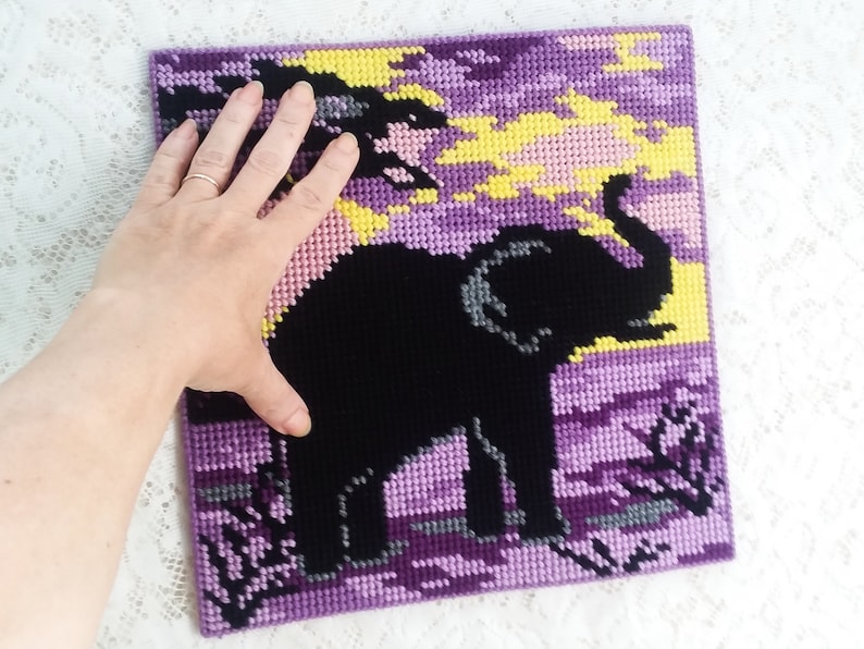 May include: Purple and black cross-stitch artwork depicting an elephant silhouette against a sunset background.