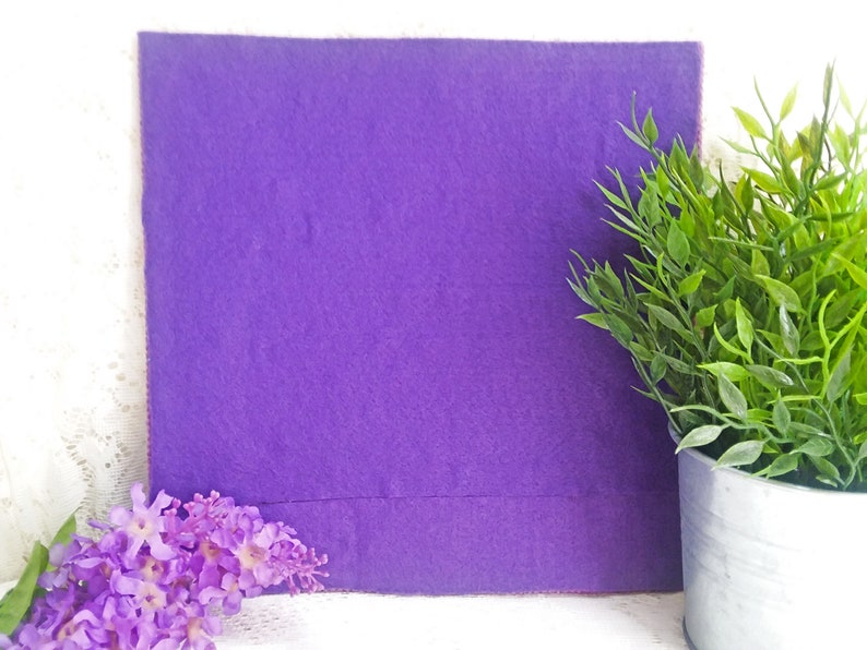 May include: A purple felt board with a smooth surface. The board is surrounded by white lace and green plants in a gray pot.