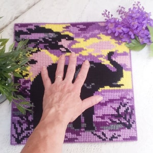 May include: Purple and yellow pixel art of an elephant with a sunset background. The art is framed and is about the size of a person's hand.