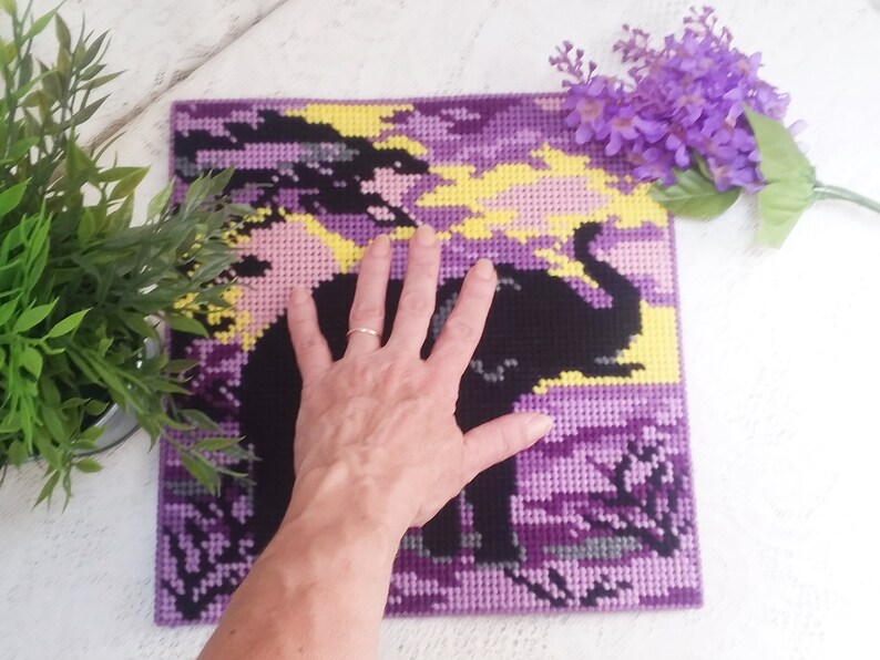 May include: Purple and yellow pixel art of an elephant with a sunset background. The art is framed and is about the size of a person's hand.