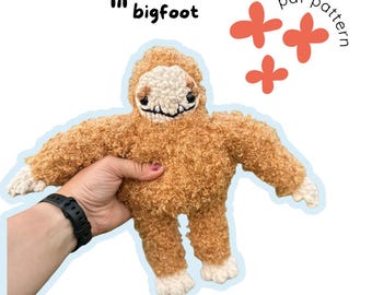 May include: A handmade, plush toy bigfoot in shades of brown and cream. The toy has a textured, curly fur-like appearance, with a light-colored face and feet. The text "lil' bigfoot" is above the toy, and "pdf pattern" is next to three orange flower shapes.