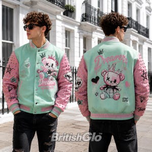 May include: A mint green and pink varsity jacket featuring a graphic of a teddy bear wearing a crown, the text "Dreamer" and "STAY CUTE," and silver studs on the sleeves. The jacket includes star and diamond graphics on the arms.