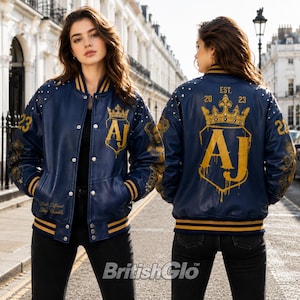 May include: A navy blue varsity jacket with gold striped ribbed cuffs and collar. The back features a large gold crown graphic above the letters AJ, with the text EST. 2023. The sleeves have gold accents and the number 23 on the shoulders.