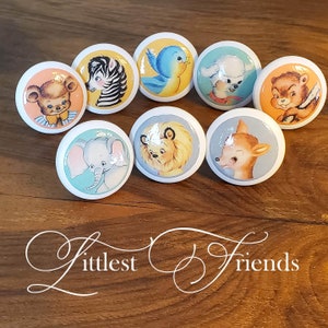 May include: Set of eight white ceramic knobs with colorful animal illustrations. The animals include a bear, zebra, bird, sheep, squirrel, elephant, lion, and deer. The knobs are labeled "littlest friends".
