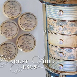May include: Five round, cream-colored drawer pulls with a floral design and the text "FAIREST Lord Jesus". The pulls are attached to a distressed, multi-colored wooden chest of drawers with blue and white striped drawers.