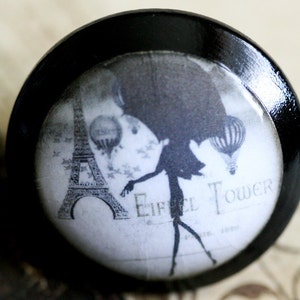May include: A black and white image of the Eiffel Tower with a silhouette of a woman in a dress holding a parasol. The text "Eiffel Tower" is printed on the image.
