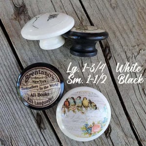 May include: Four decorative cabinet knobs in white and black. One knob has a black base with a white top. The other knobs have a white base with a black top. The knobs have various designs and text.