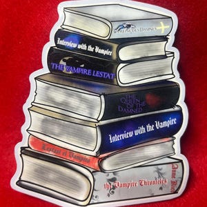 Könnte beinhalten: Ein Aufkleber mit einem Stapel Bücher aus Anne Rices Vampir-Chroniken-Reihe. Zu den Titeln gehören "Interview with the Vampire", "The Vampire Lestat" und "The Queen of the Damned". Der Aufkleber hat einen weißen Rand und einen roten Hintergrund.