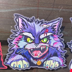 May include: A sticker featuring a cartoon cat with a menacing expression. The cat has purple fur, green eyes, and a bloody wound with the number 19. It has a gold collar and is baring its teeth.