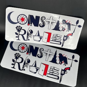 May include: Two rectangular white stickers featuring the text CONSTANT READER in dark blue. The letters are replaced by icons including a crescent moon, wheel, rose, lobster, sailboat, open door with red trim, tower, dog, books, and a revolver.