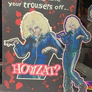 May include: A greeting card with the text "I wanna take your trousers off..." and "HOWZAT?" features an illustration of a person in a blue jumpsuit. A sticker of the same illustration is also present.