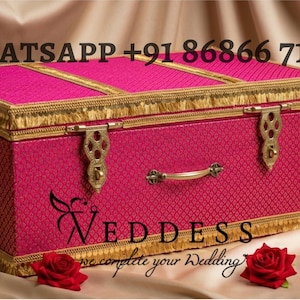 May include: A vibrant pink decorative chest with gold detailing. The chest features a textured pattern, gold fringe, and ornate hardware. The image also includes red roses and a gold earring.