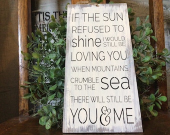 May include: White wooden sign with black text that reads "If the sun refused to shine I would still be loving you when mountains crumble to the sea there will still be you & me".