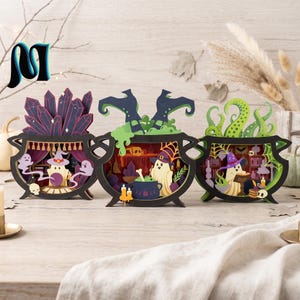 May include: Three layered wooden cauldron decorations featuring intricate cutouts of ghosts, witch hats, crystals, tentacles, and potion ingredients. Each black-framed display showcases a detailed scene with colorful elements like purple crystals, green slime, and orange accents.