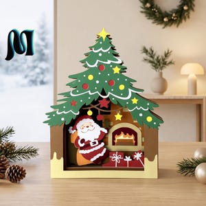 Op de afbeelding: Een gelaagde houten kerstdecoratie met een groene boomtop met gele en rode ornamenten, een centrale scène met de Kerstman naast een brandende open haard en rode geschenken aan de basis, geplaatst in een bruin huisvormig frame.