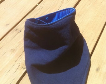 May include: A dark blue fleece neck warmer with a blue satin lining. The neck warmer is folded and lying on a wooden surface.