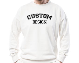 May include: White sweatshirt with a black print that says "CUSTOM DESIGN" in a collegiate font.