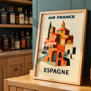 May include: A framed vintage travel poster for Air France, featuring a colorful illustration of a Spanish town. The poster has a light wood frame and the text "Air France" and "Espagne" in navy blue.