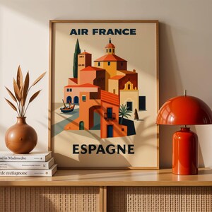 May include: A framed vintage travel poster for Air France, featuring a colorful illustration of a Spanish town with red-tiled roofs and a small boat. The poster has the words "AIR FRANCE" and "ESPAGNE" in navy blue.