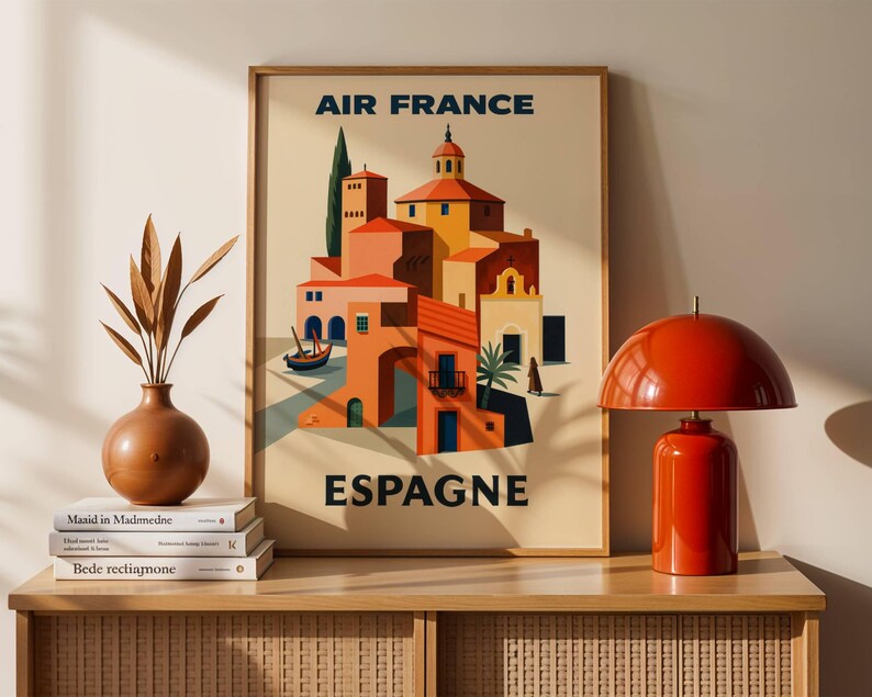 May include: A framed vintage travel poster for Air France, featuring a colorful illustration of a Spanish town with red-tiled roofs and a small boat. The poster has the words "AIR FRANCE" and "ESPAGNE" in navy blue.