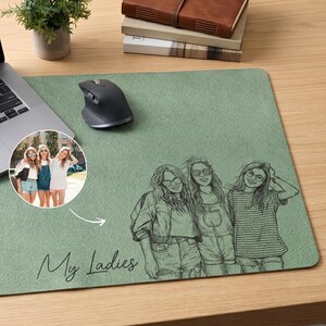 Peut inclure: Tapis de souris vert sauge avec une illustration personnalisée de trois femmes et le texte "My Ladies". Un ordinateur portable, une souris et une photo des femmes sont également sur le bureau.