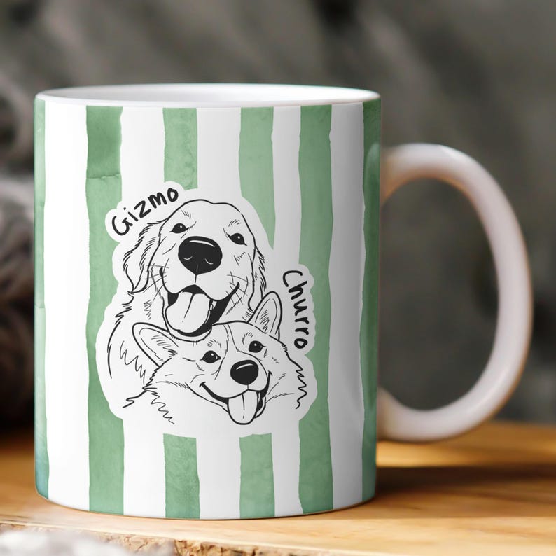 May include: White ceramic mug with a green watercolor stripe design. The mug features a black and white illustration of two dogs, a Golden Retriever and a Corgi, with the names "Gizmo" and "Churro" written above them.