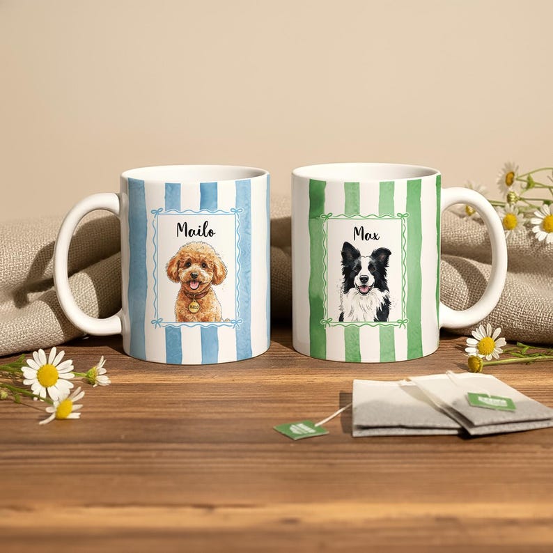 May include: Two white ceramic mugs with dog portraits. One mug has blue and white stripes and a portrait of a poodle named "Mailo." The other mug has green and white stripes and a portrait of a border collie named "Max."
