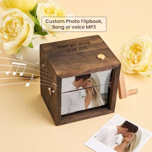 May include: A dark wooden photo flipbook featuring a couple kissing. The flipbook is engraved with "I love you always 22.07.2025". The text "Custom Photo Flipbook, Song or voice MP3" is also visible on the flipbook.