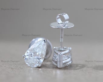 Può includere: Un paio di orecchini a lobo con diamanti. Ogni orecchino presenta un diamante trasparente a forma di pera incastonato in una montatura in metallo argentato. Gli orecchini hanno una chiusura a perno e farfalla. Lo sfondo è di colore marrone chiaro neutro.