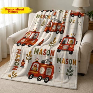 Può includere: Una coperta in pile color crema con un motivo ripetuto di camion dei pompieri rossi, idranti e rametti verdi. Il nome Mason è stampato in grandi lettere arancione-marrone in grassetto su tutto il design, sopra un sottile sfondo a griglia.