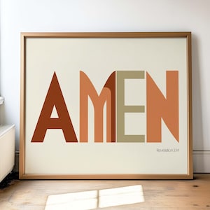 May include: A framed print with the word "AMEN" in large, stylized letters in shades of brown, orange, and beige. The text "Revelation 3:14" is printed in smaller font below the word "AMEN".