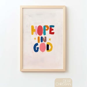 Puede incluir: Una impresión artística enmarcada con las palabras "HOPE IN GOD" en letras de bloque coloridas. La obra de arte presenta un fondo claro con el texto en rojo, azul, amarillo, rosa y negro. También se incluyen dos estrellas amarillas.