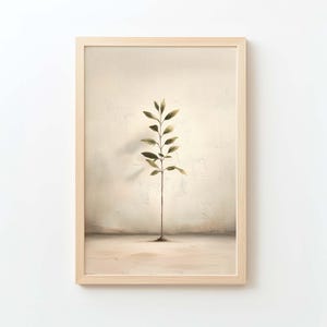 May include: A framed art print featuring a minimalist botanical illustration. The artwork depicts a slender plant with olive-green leaves against a neutral, textured background. The frame is a light wood tone, adding a natural aesthetic to the piece.