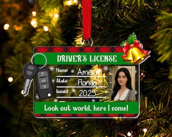 May include: A personalized Christmas ornament shaped like a driver's license, featuring a photo, name, and the text "Look out world, here I come!". The ornament includes a car key and a red ribbon for hanging.