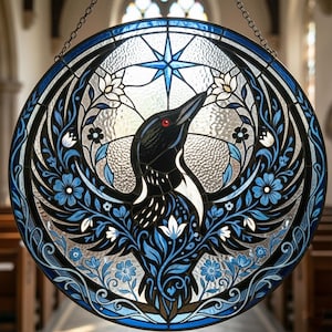 May include: Circular stained glass window featuring a black and white bird with a red eye, surrounded by blue floral patterns and a blue star. The window is framed with a dark blue border and hangs from a chain.