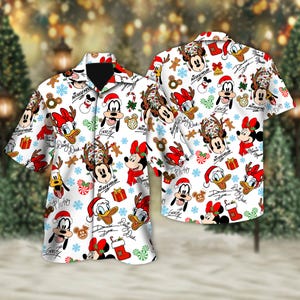 May include: White button-down shirt with a festive pattern featuring Disney characters such as Mickey Mouse, Donald Duck, and Goofy in Santa hats and reindeer antlers. The design includes snowflakes, gifts, and candy canes.