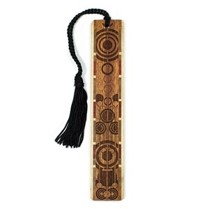 May include: A wooden bookmark with a geometric design in shades of brown and red. The bookmark has a black tassel.