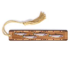 May include: A wooden bookmark with a tassel features a colorful image of four trout swimming in a row. The bookmark has a wood grain pattern and a red and brown inlay.