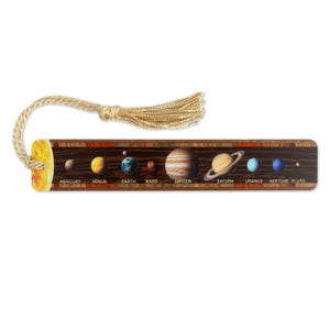 Könnte beinhalten: Ein Holz-Lesezeichen mit einem goldenen Quastenbesatz zeigt eine farbenfrohe Illustration der Sonne und der Planeten unseres Sonnensystems. Die Planeten sind mit ihren Namen beschriftet: Merkur, Venus, Erde, Mars, Jupiter, Saturn, Uranus, Neptun und Pluto.