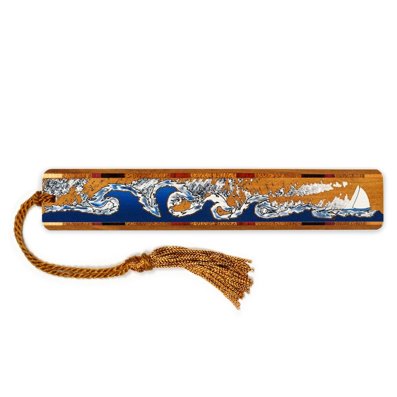 May include: A wooden bookmark featuring a blue and white wave design with a sailboat. The bookmark has a gold tassel.