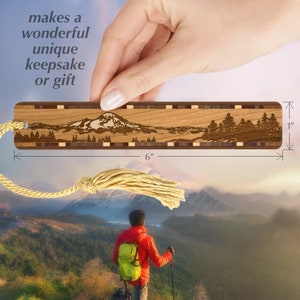 May include: A wooden bookmark with a laser-engraved image of a mountain range. The bookmark is 6 inches long and 1 inch wide. It has a brown tassel attached to it.